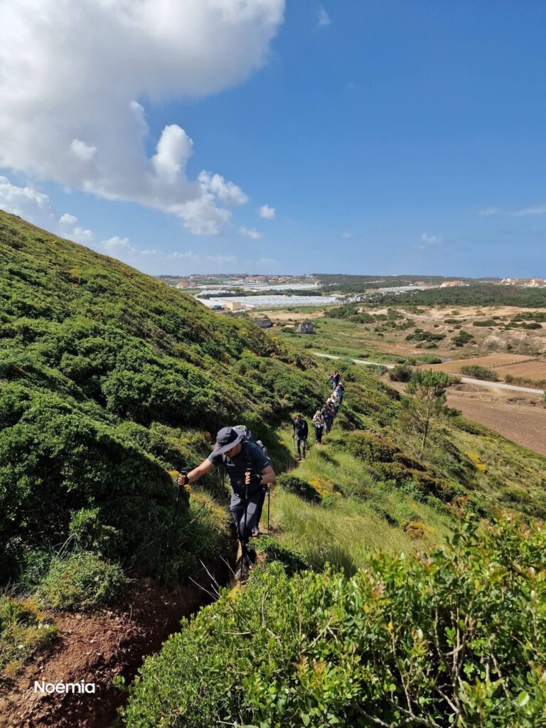 Pessoa com mochila a fazer caminhada num trilho natural junto às falésias e mar em Portugal