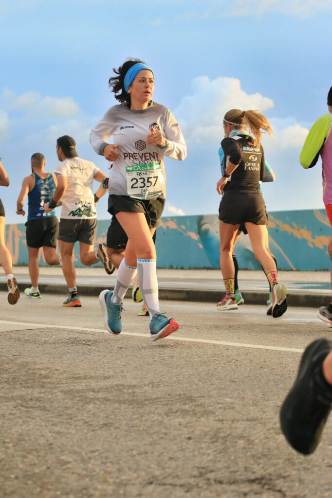 Mulher sorridente a correr num passadiço de madeira perto da praia em Portugal