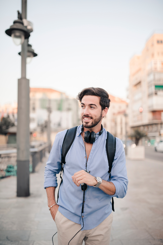 Homem sorridente e relaxado a passear pelas ruas de uma cidade portuguesa.